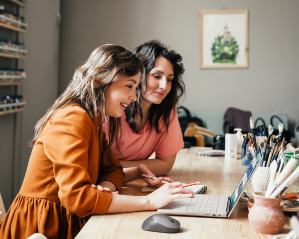 Dwie pracownice rozmawiają o swojej firmie na warsztatach przy użyciu notebooka Dell 14 Premium
