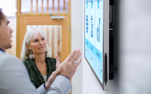 Wsp&oacute;łpracownicy omawiający elementy wyświetlane na dużym wyświetlaczu firmy Dell.