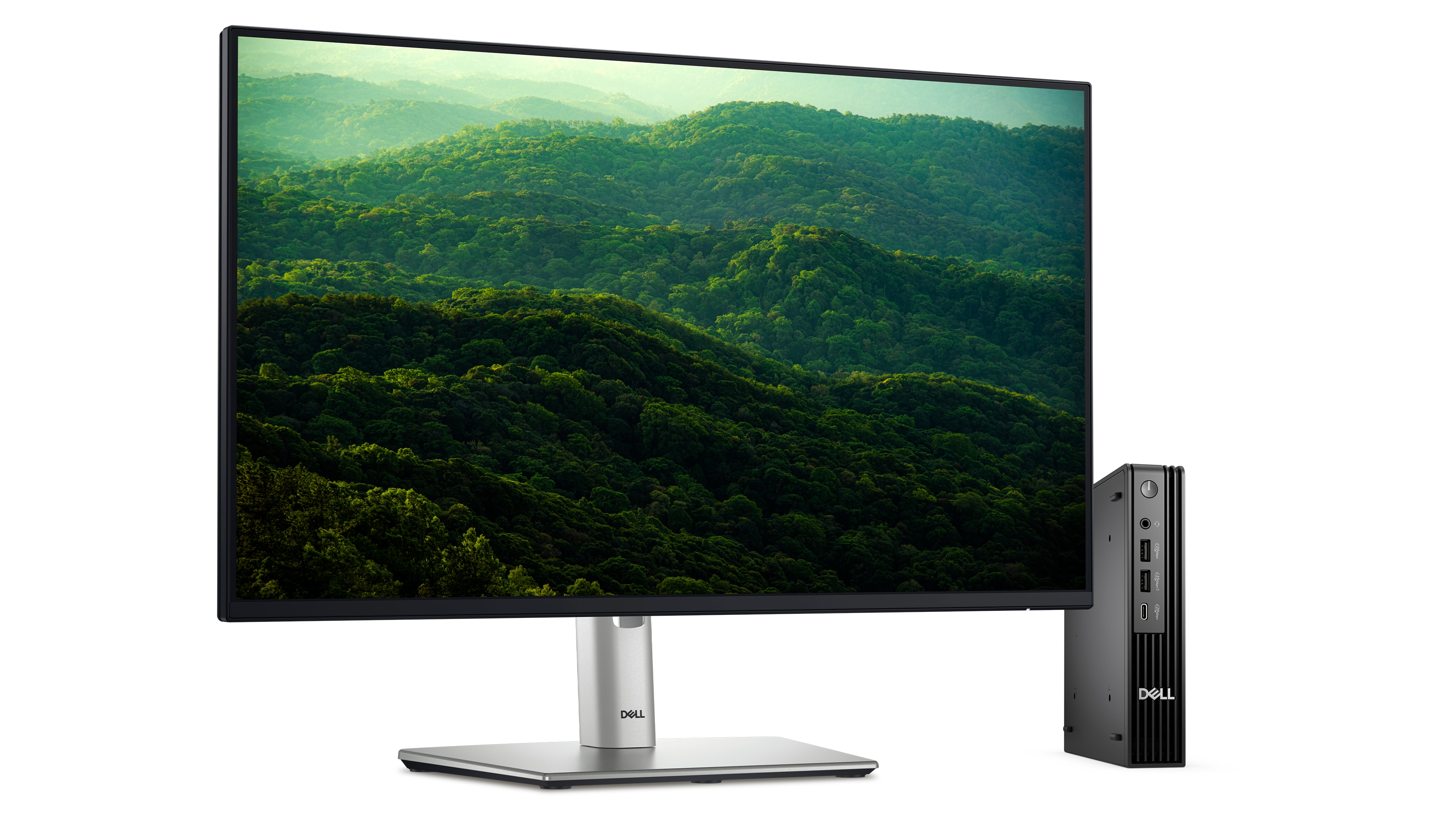 Dell Pro Micro obok monitora Dell p2425h na białym tle. Na ekranie widoczne zielone drzewa rosnące na zboczach wzgórz.