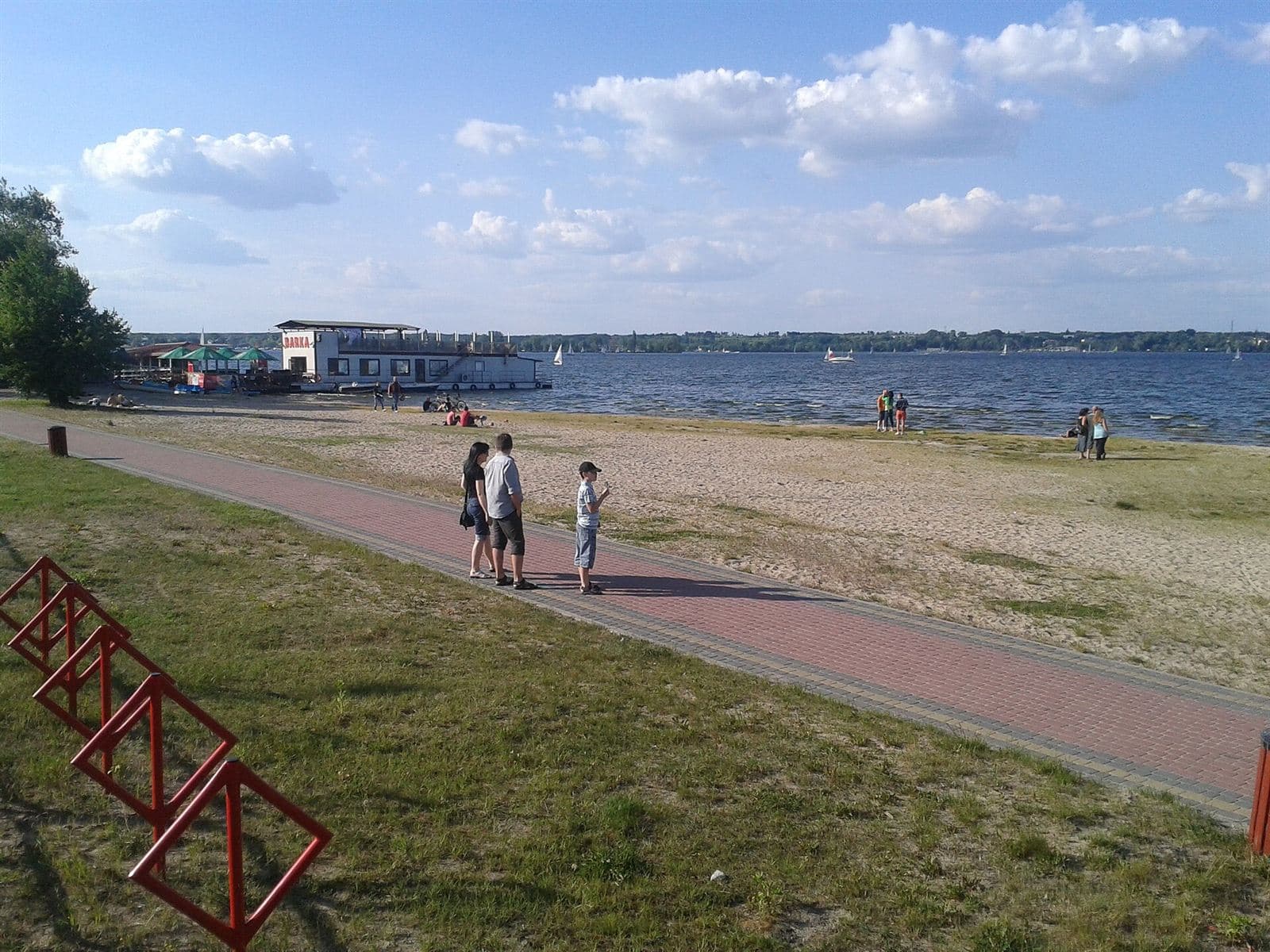 Piaszczysta plaża w Nieporęcie latem, w tle żagle na jeziorze